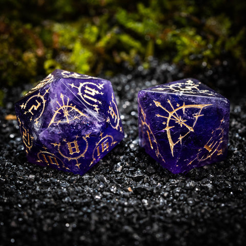two purple dices with gold designs on them