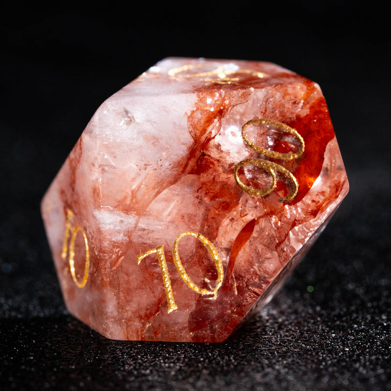 a close up of a red and gold dice on a black surface