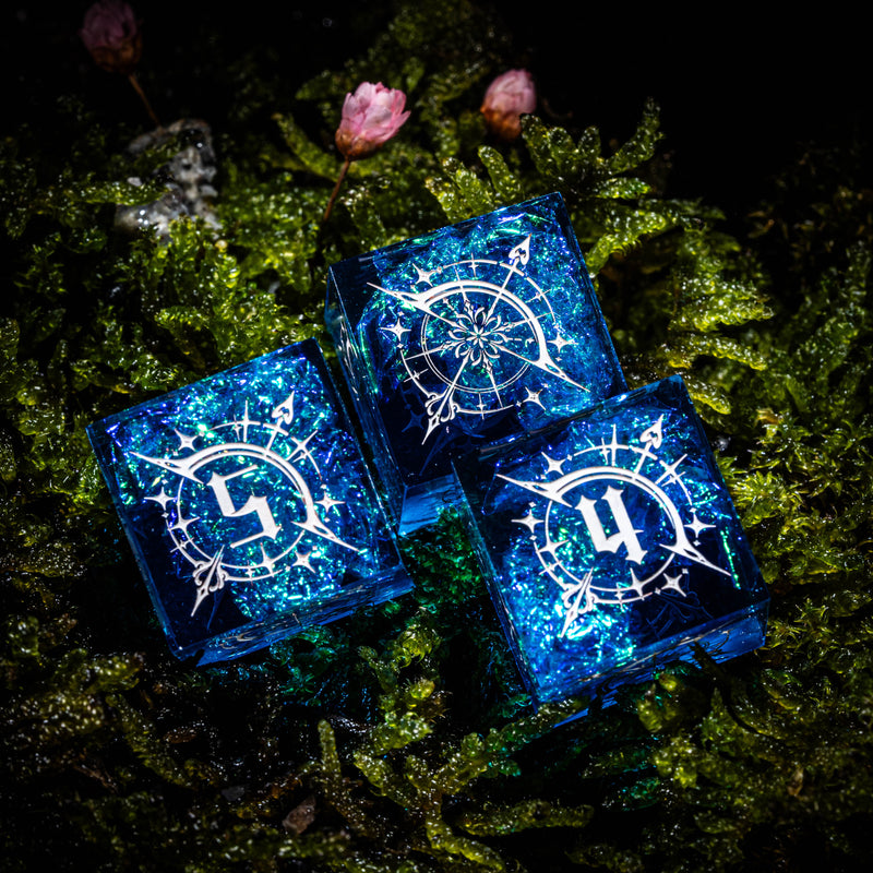 three blue dices sitting on top of a moss covered ground