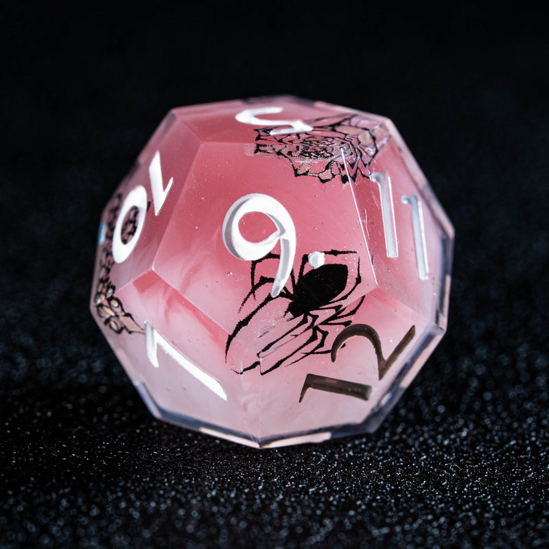 a close up of a pink dice on a black surface