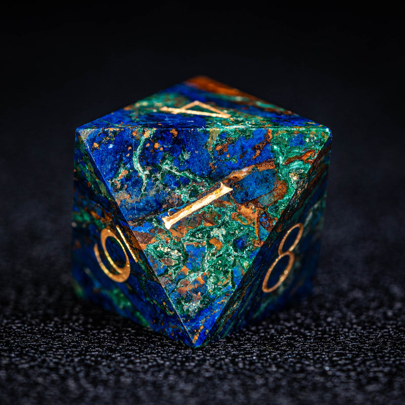 a blue and green marbled dice sitting on a black surface